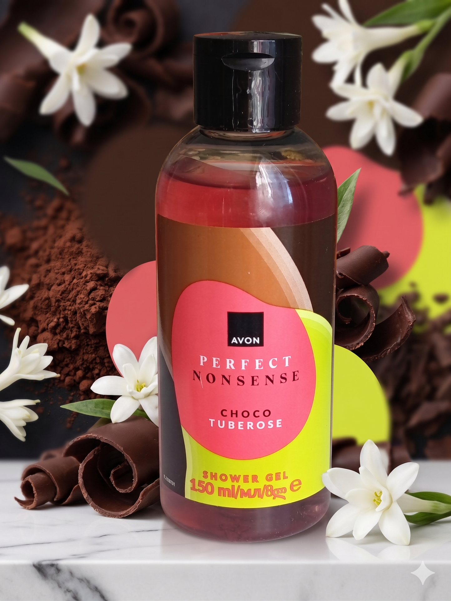 "Flacon de gel douche Avon 'Perfect Nonsense - Choco Tuberose' mis en avant sur un marbre blanc, entouré de fleurs de tubéreuse blanches, de copeaux de chocolat noir et de poudre de cacao en fond.