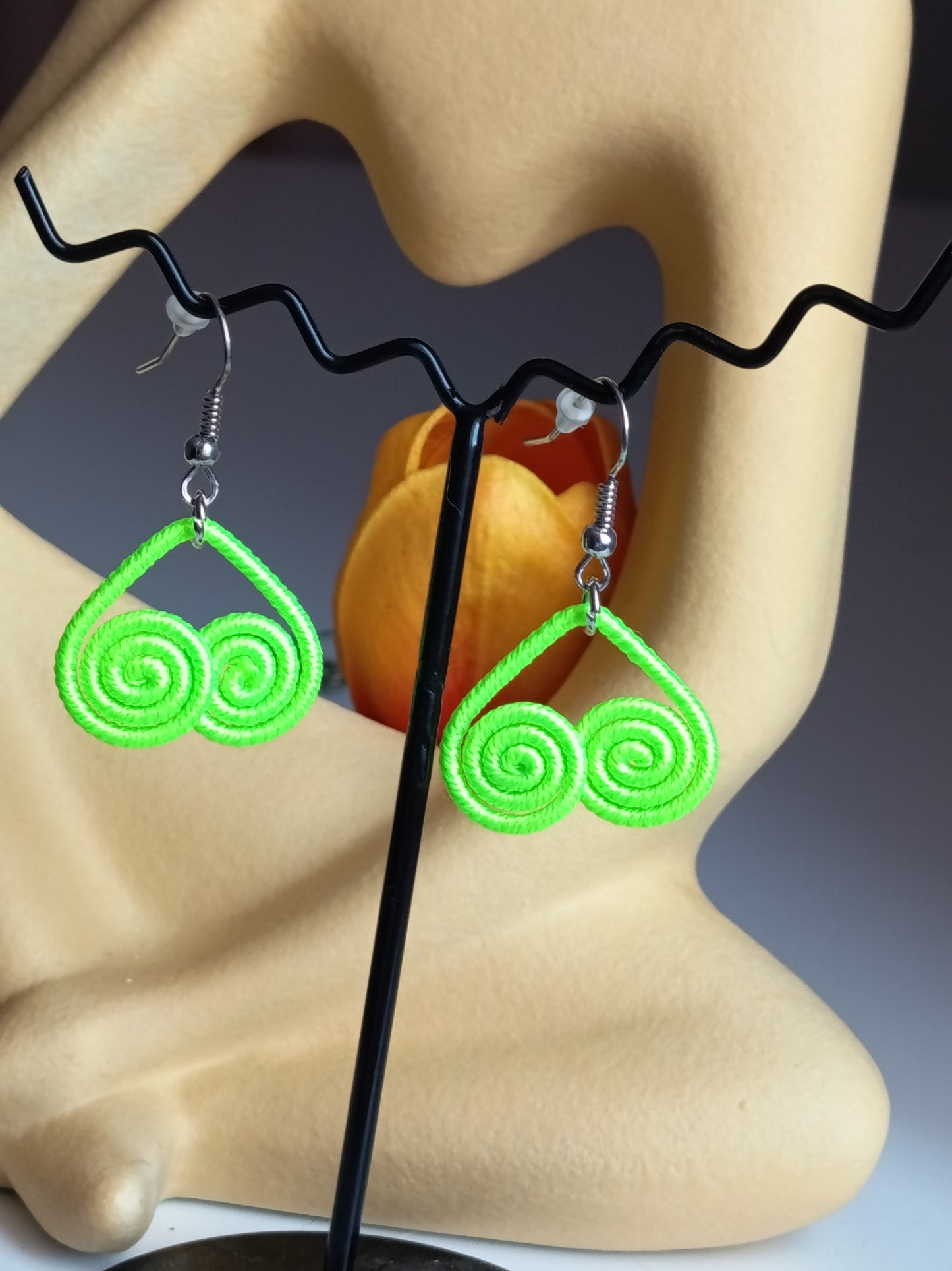 Profil des boucles d'oreilles vert néon pendante sur son support, soulignant sa légèreté et son design aérien