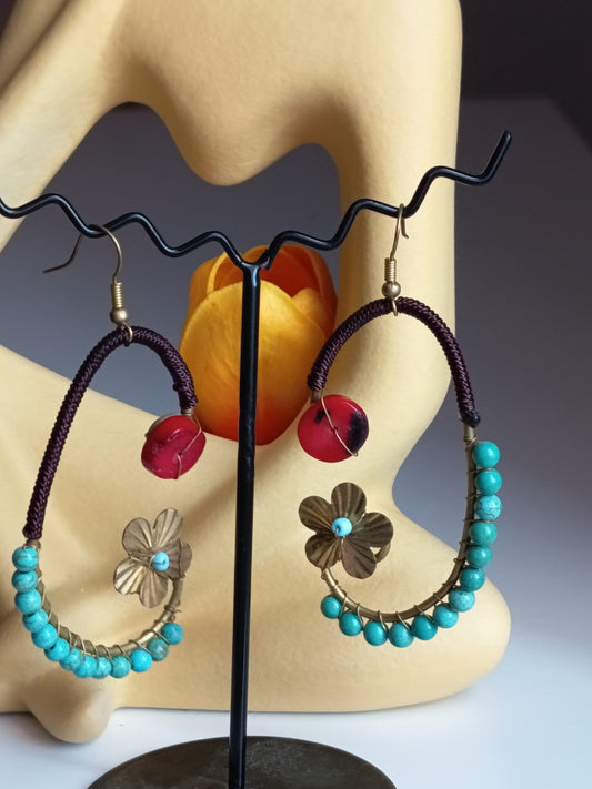 Paire de boucles d'oreilles artisanales créoles ornées de perles turquoise, d'une breloque fleur dorée et d'une perle rouge centrale.