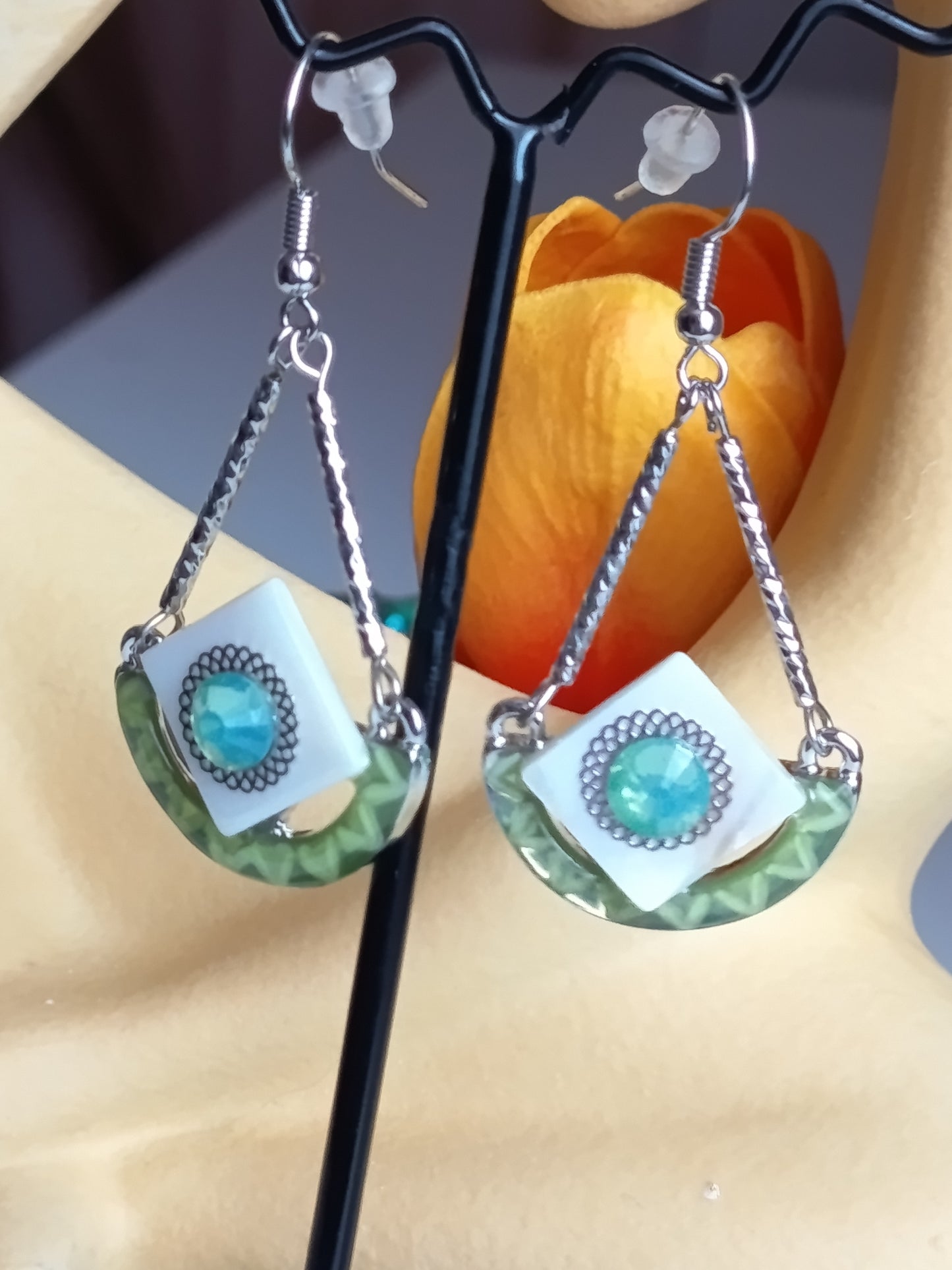 Boucles d'oreilles pendantes géométriques avec insert blanc et pierre centrale bleu-vert, design moderne et élégant