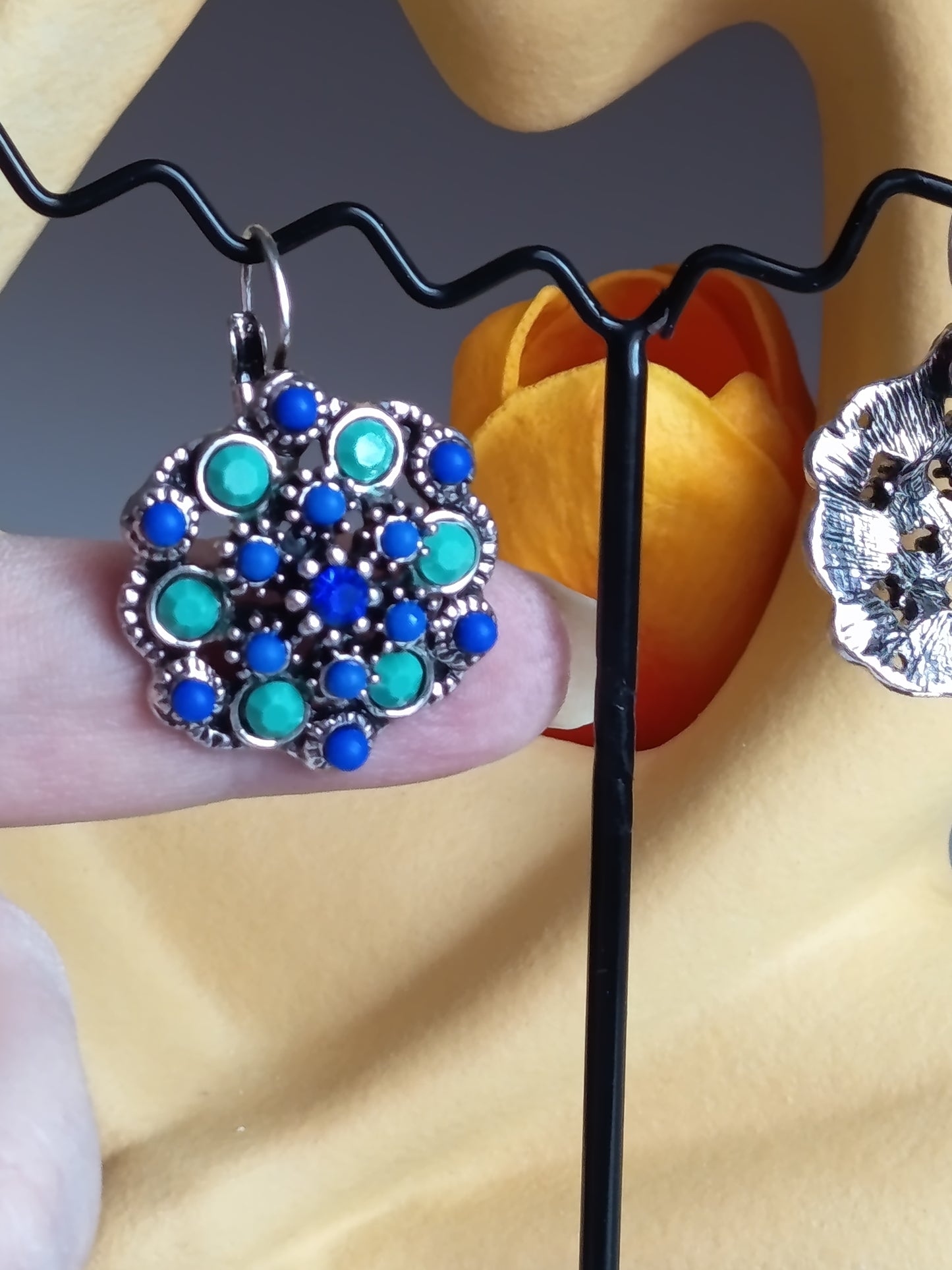 "Boucles d'oreilles fleuries tenues en main pour montrer l'échelle et la finesse du design." ✋🌸