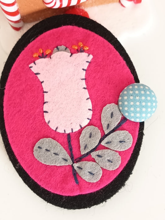 Broche unique en feutrine rose fuchsia avec une tulipe rose pâle brodée et bouton à pois bleu. 